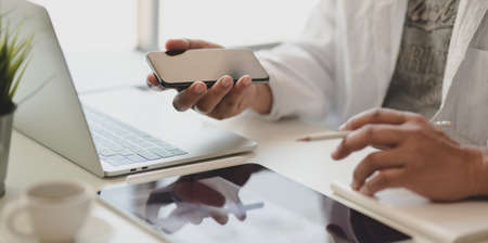 Cropped shot of young male freelancer touching his smartphone in the modern office while preparing...