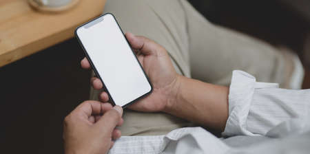 Close-up view of businessman holding blank screen smartphone while sitting on a chairの写真素材