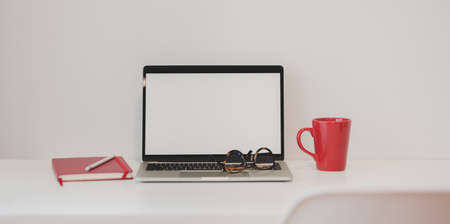 Close-up view of modern office with laptop computer, red notebook and red coffee cupの写真素材