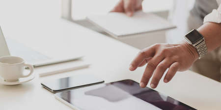 Close-up view of businessman working on his project while preparing tablet and other office suppliesの写真素材