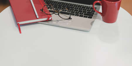Cropped shot of trendy office with laptop computer and red notebook with other office suppliesの写真素材