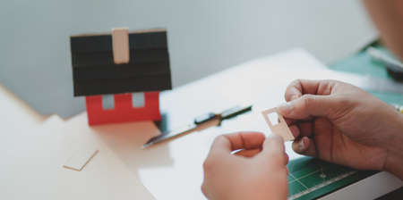 Close-up view of young male architect making small house model while assemble other componentsの写真素材