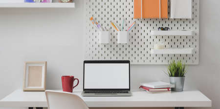 Minimal home office with open blank screen laptop computer with stationary and office suppliesの写真素材