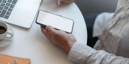 Close-up view of businessman working on his project while using blank screen smartphoneの写真素材