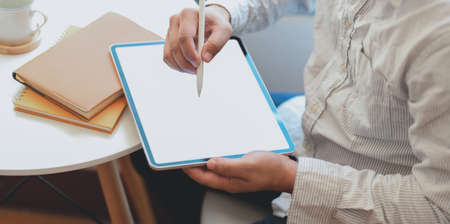 Cropped shot of businessman writing the idea on blank screen tablet in his comfortable workspaceの写真素材