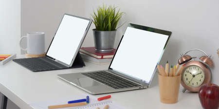 Blank screen laptop computer and tablet with stationary and decorations on modern workplaceの写真素材