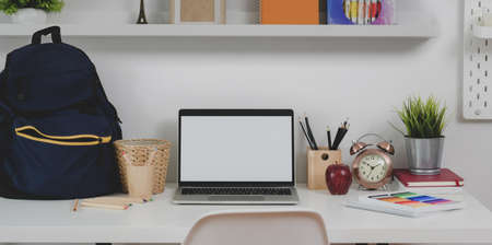 Minimal comfortable workplace with blank screen laptop with stationary and school bag on white wooden tableの写真素材
