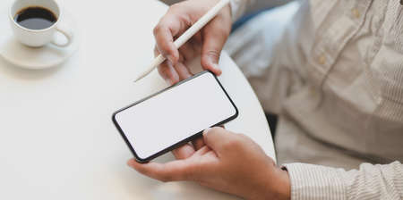 Young professional businessman working on his project while using blank screen smartphone in his...