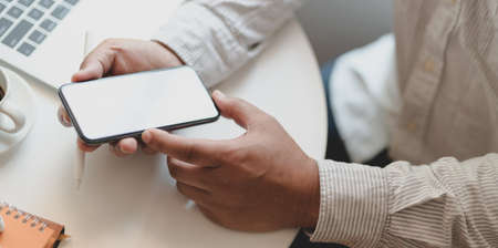Cropped shot of businessman working on his project while using blank screen smartphoneの写真素材
