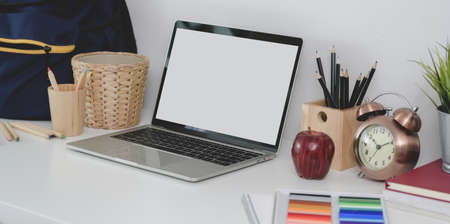 Cropped shot of comfortable workplace with blank screen laptop with stationary and school bagの写真素材