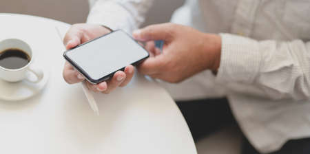 Young professional businessman working on his project while using blank screen smartphone in his workspaceの写真素材