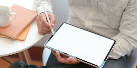 Young male freelancer writing his idea concept on blank screen tablet in modern comfortable workplaceの写真素材
