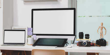 Blank screen desktop computer and laptop computer with office supplies in modern workspaceの写真素材