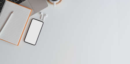 Overhead shot of comfortable workspace with blank screen smartphone on white wooden desk with office supplies and copy spaceの写真素材