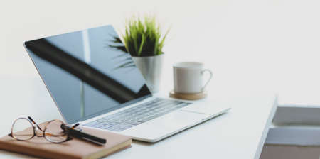 Open laptop computer with coffee cup and office supplies in comfortable workplace near the windowsの写真素材