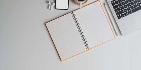 Overhead shot of comfortable workplace with open blank notebook on white desk background with office accessoriesの写真素材