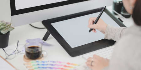 Close-up view of young professional female designer editing her project with digital tablet in comfortable workspaceの写真素材