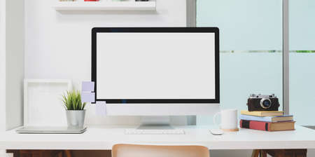 Blank screen desktop computer with office supplies and mock up frame in minimal modern workplaceの写真素材