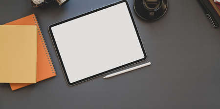 Overhead shot of blank screen tablet on dark modern workplace with laptop computer and other office suppliesの写真素材