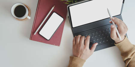 Top view of young man working on his project with tablet in comfortable workplace with office suppliesの写真素材