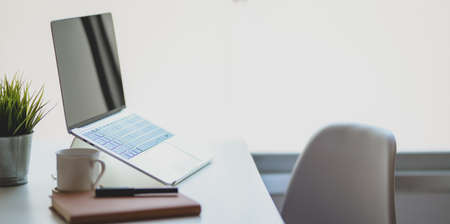 Open laptop computer with coffee cup and office supplies in comfortable workplace near the windowsの写真素材