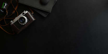 Overhead shot of dark luxury workplace with camera and office supplies on black leather deskの写真素材