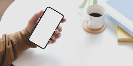 Cropped shot of man holding blank screen smartphone while working on his project in comfortableの写真素材