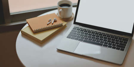 Cropped shot of minimal workplace with laptop computer with notebook and office supplies near the windowsの写真素材