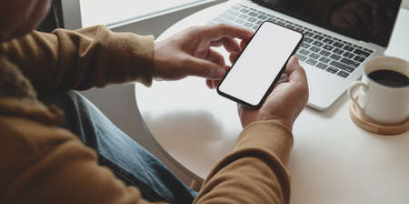 Cropped shot of man holding blank screen smartphone while working on his project in comfortableの写真素材