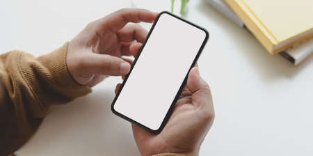 Close-up view of man holding blank screen smartphone while working on his project in comfortableの写真素材