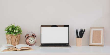 Minimal workspace with open blank screen laptop computer and office supplies on white wooden tableの写真素材