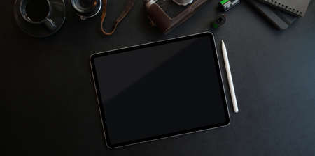 Dark trendy workspace with tablet and office supplies on black leather background, Top view with copy spaceの写真素材