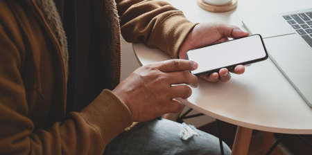 Close-up view of man holding blank screen smartphone while working on his project in comfortableの写真素材