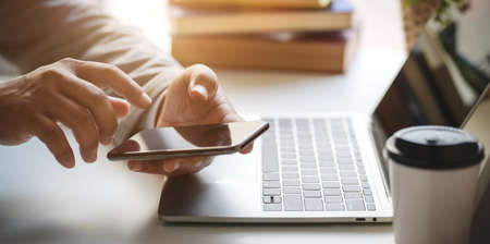 Close-up view of professional businessman holding blank screen smartphone while working in his officeの写真素材