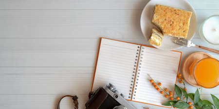 Overhead shot of cozy workspace with blank notebook with toast bread and a glass of orange juice on white wooden table backgroundの写真素材