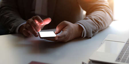Close-up view of professional businessman holding blank screen smartphone while working in his...