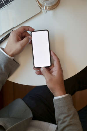 Top view of young businessman holding blank screen smartphone while working on his projectの写真素材