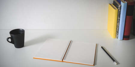 Close-up view of minimal workplace with open blank notebook, office supplies, coffee cup and copy spaceの写真素材