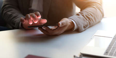 Cropped shot of professional businessman holding smartphone while working in his comfortable office roomの写真素材