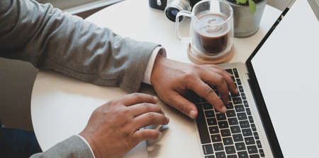 Close-up view of young businessman working with laptop computer while working on his projectの写真素材