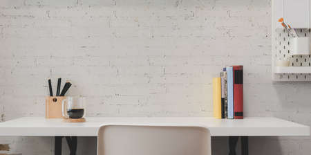 Minimal home-office with office supplies and decorations on white wooden table background and white brick wallの写真素材