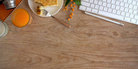 Top view of cozy workspace with a glass of orange juice and toast bread on wooden table with copy spaceの写真素材