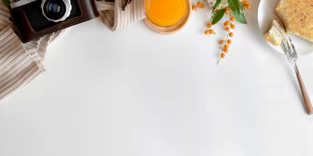 Top view of comfortable workspace with camera and breakfast on white table with copy spaceの写真素材