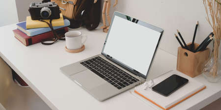Cropped shot of modern office room with open blank screen laptop computer with smartphone and the office suppliesの写真素材
