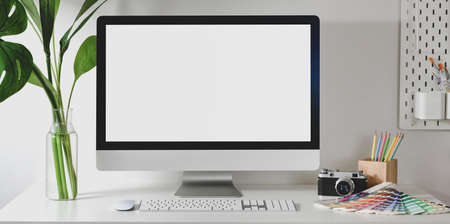 Modern designer workplace with blank screen desktop computer with camera and colour swatches on white tableの写真素材