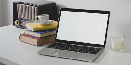 Blank screen laptop computer with office supplies and vintage radio in minimal white office styleの写真素材