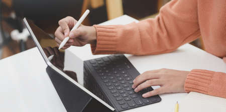 Cropped shot of young female working on her current project with tablet in modern office room の写真素材