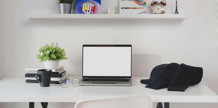 Minimal workplace with open blank screen laptop computer with blue sweater and office supplies の写真素材