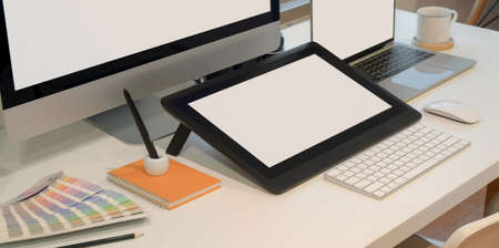 Close-up view of designer workplace with blank screen digital tablet with desktop computer with office supplies の写真素材