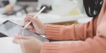 Cropped shot of young female working on her current project with tablet in modern office roomの写真素材